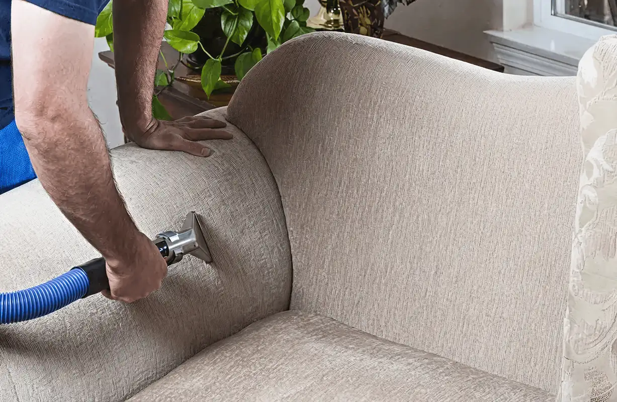 Professional upholstery cleaner deep-cleaning a fabric sofa with a handheld extraction tool and hose, San Jose, CA.